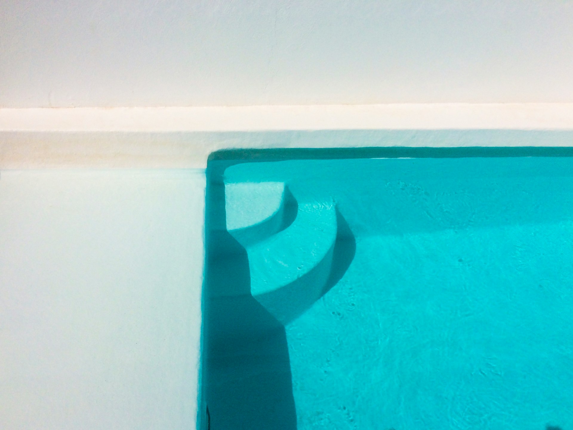 a blue swimming pool with a white wall